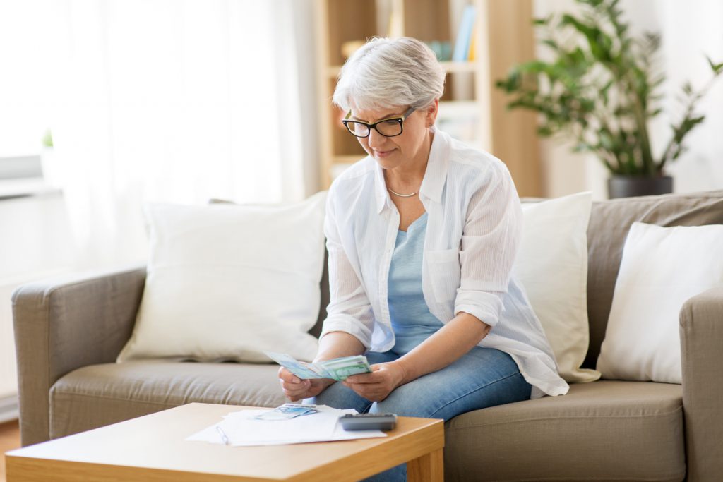 senior woman counting money at home | Pension de reversion Femme retraitée veuve calculant montant réversion