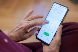 Mains d'une personne âgée composant un numéro de téléphone pour contacter la CNRACL.