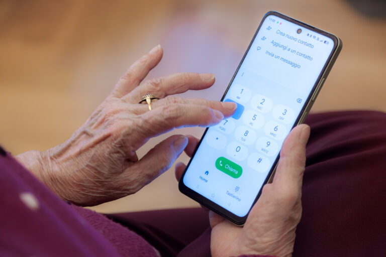 Mains d'une personne âgée composant un numéro de téléphone pour contacter la CNRACL.