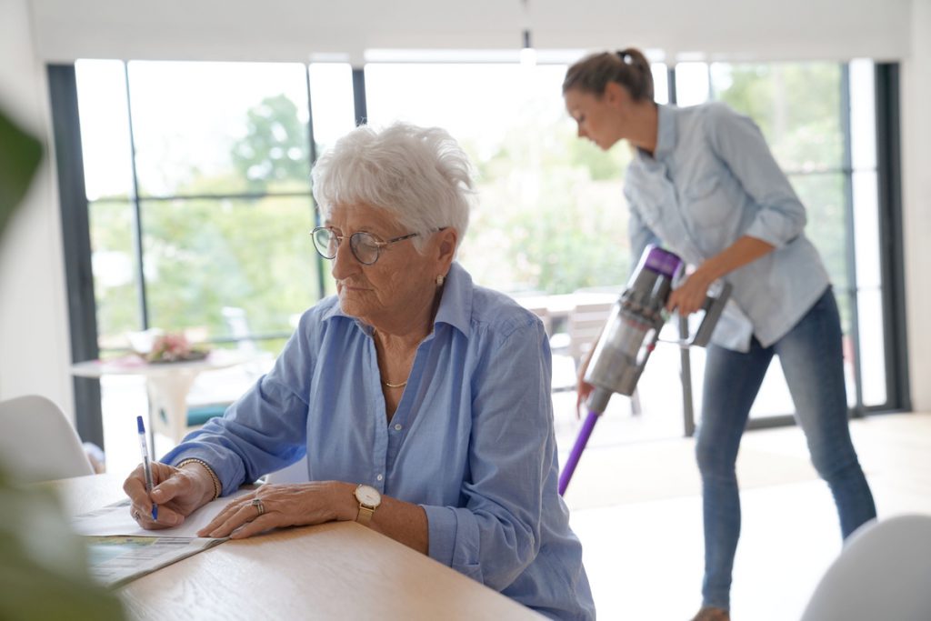 Aide à domicile faisant le ménage chez personne âgée