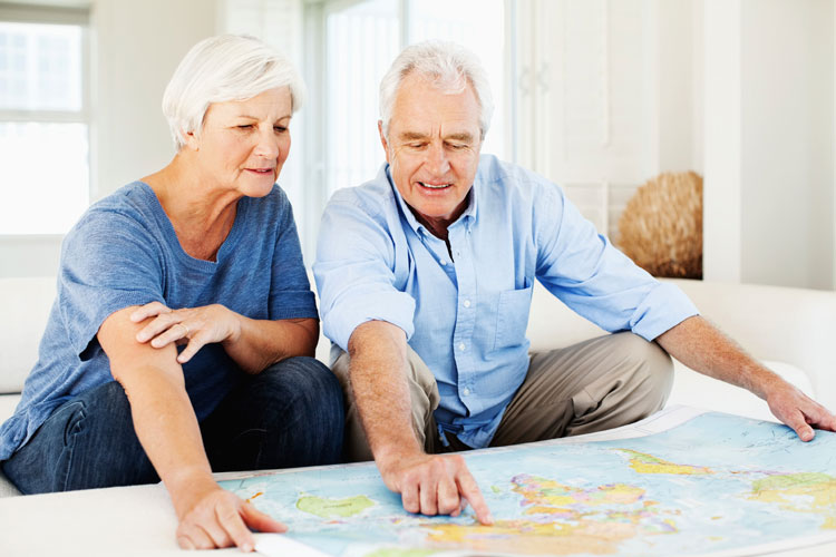 couple senior devant carte du monde