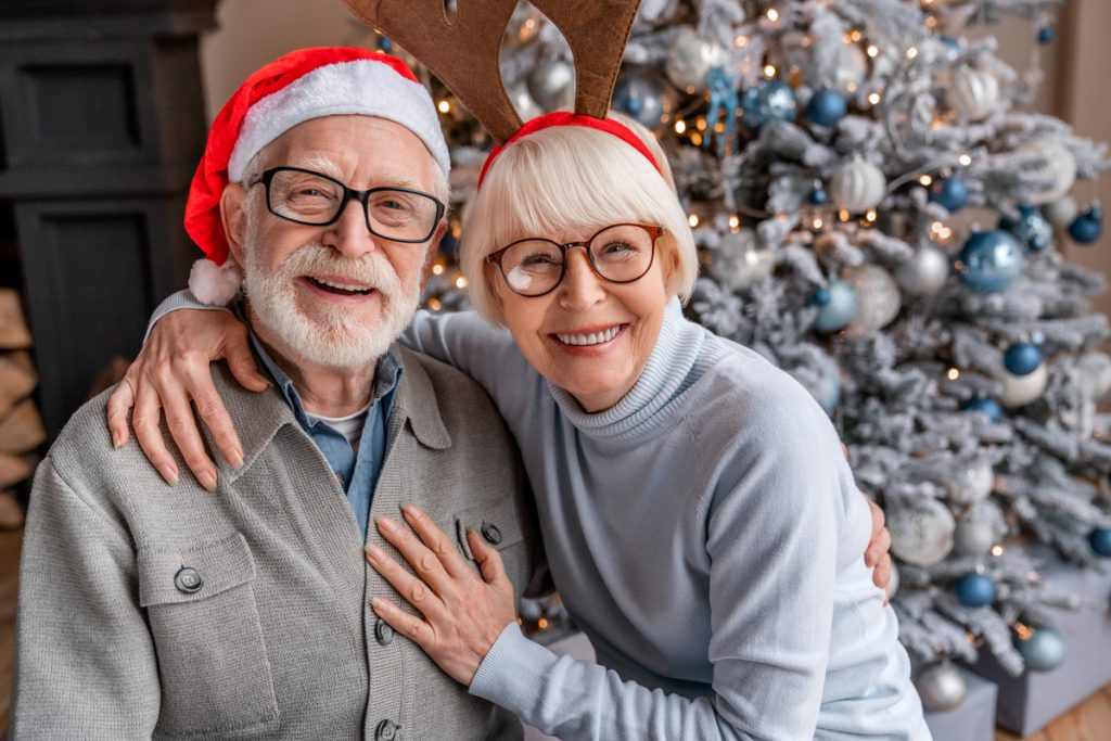Portrait of happy smiling senior couple in santa hats celebrating at home | Pension de reversion Versement de la prime de Noël aux retraités