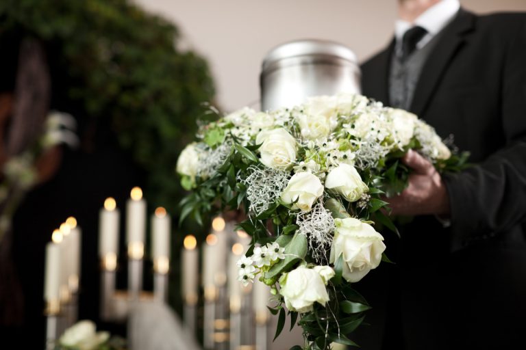 Urne argentée entouré couronne fleurs cendres défunt