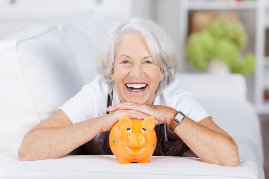 Retraitées souriante appuyée sur une tirelire