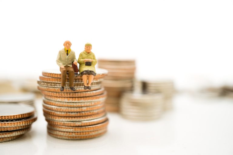 retraités assis sur tas pièces monnaie