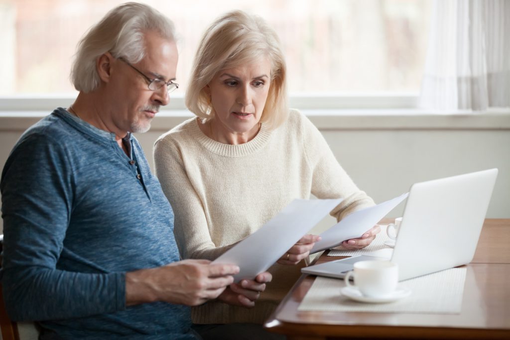 Serious worried senior couple reading documents calculating bill | Pension de reversion Couple personnes âgés lisant contrat assurance vie