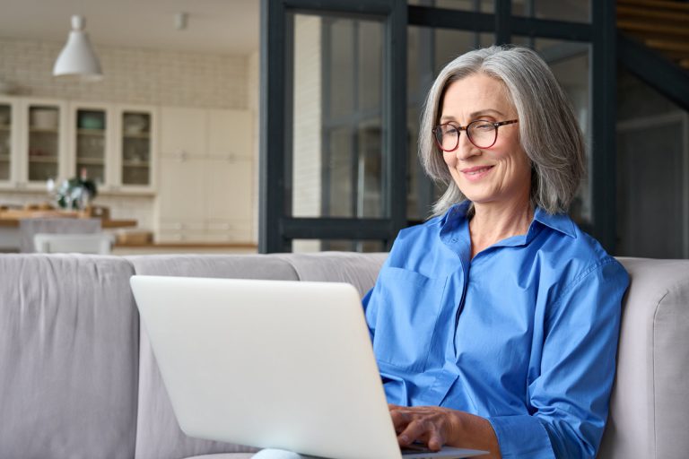 Femme âge mûr devant ordinateur sur canapé