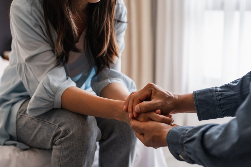 Young man comforting and supporting a sad woman who is in serious trouble at home, Consolation and encouragement concept | Pension de reversion homme et femme se tenant la main pour faire face au deuil