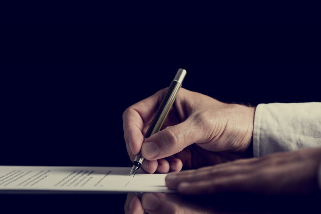 Signing a contract over dark background | Pension de reversion