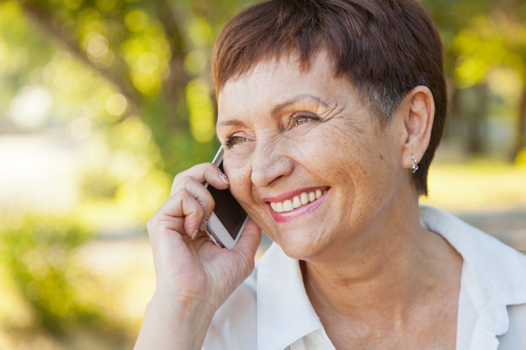 beautiful woman of 50 years with a mobile phone outdoors | Pension de reversion femme appelant le cicas agirc-arrco au téléphone