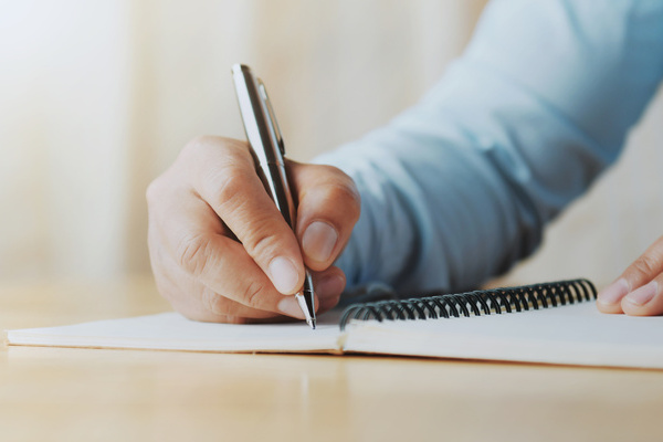 hand of woman holding pen with writing on notebook in office | Pension de reversion