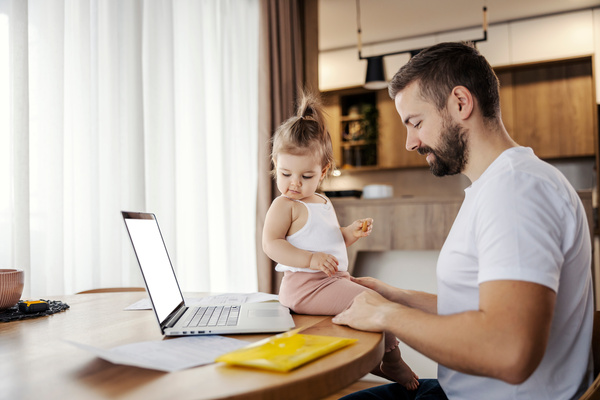 A stay at home dad is working on a laptop while his toddler is h | Pension de reversion