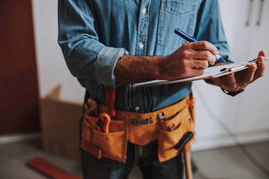 Construction worker writing on clipboard stock photo | Pension de reversion aide aux travaux d'amélioration et d'adaptation du logement