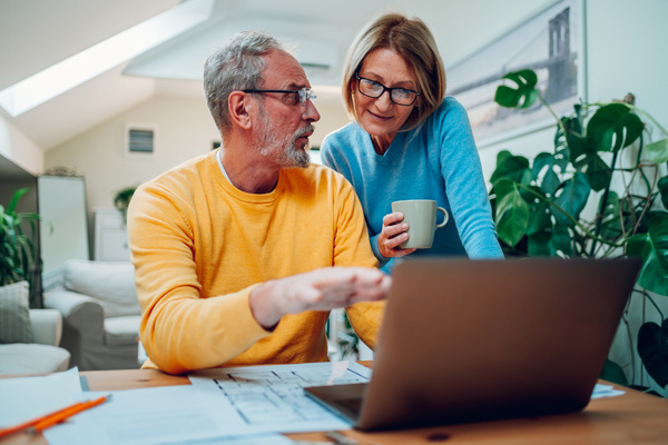 Senior middle aged happy couple using laptop together at home | Pension de reversion aide factures énergie
