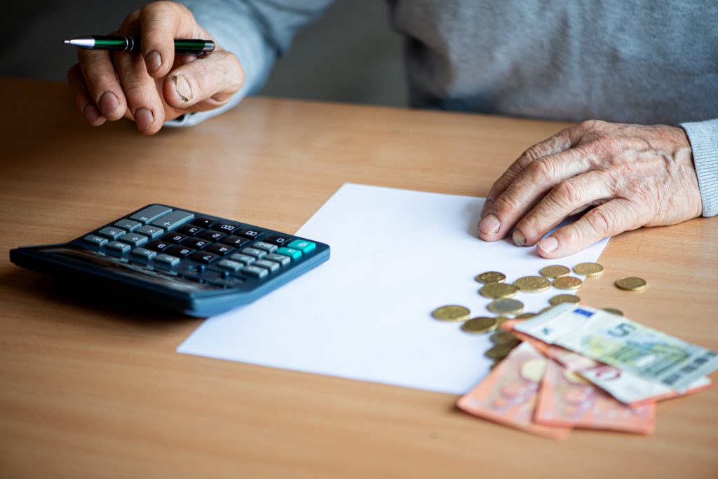 Hands of old senior man with calculator and bills counting euro | Pension de reversion senior calculant le montant de sa retraite minimum