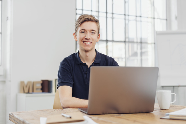 Young cheerful man sitting in front of laptop | Pension de reversion carrière longue