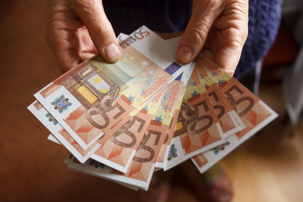 elderly woman holds in hands euro banknotes | Pension de reversion montant minimum retraite