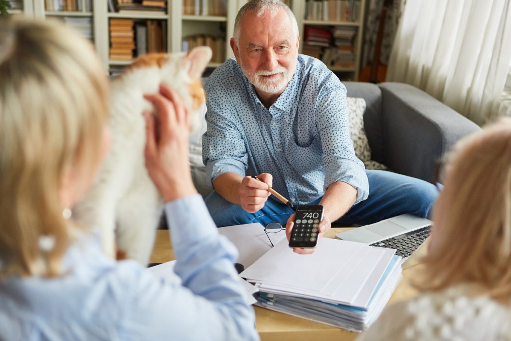 Finanzberater gibt Tipps zum Geld sparen bei der Vorsorge | Pension de reversion Homme âgé avec calculette à la main