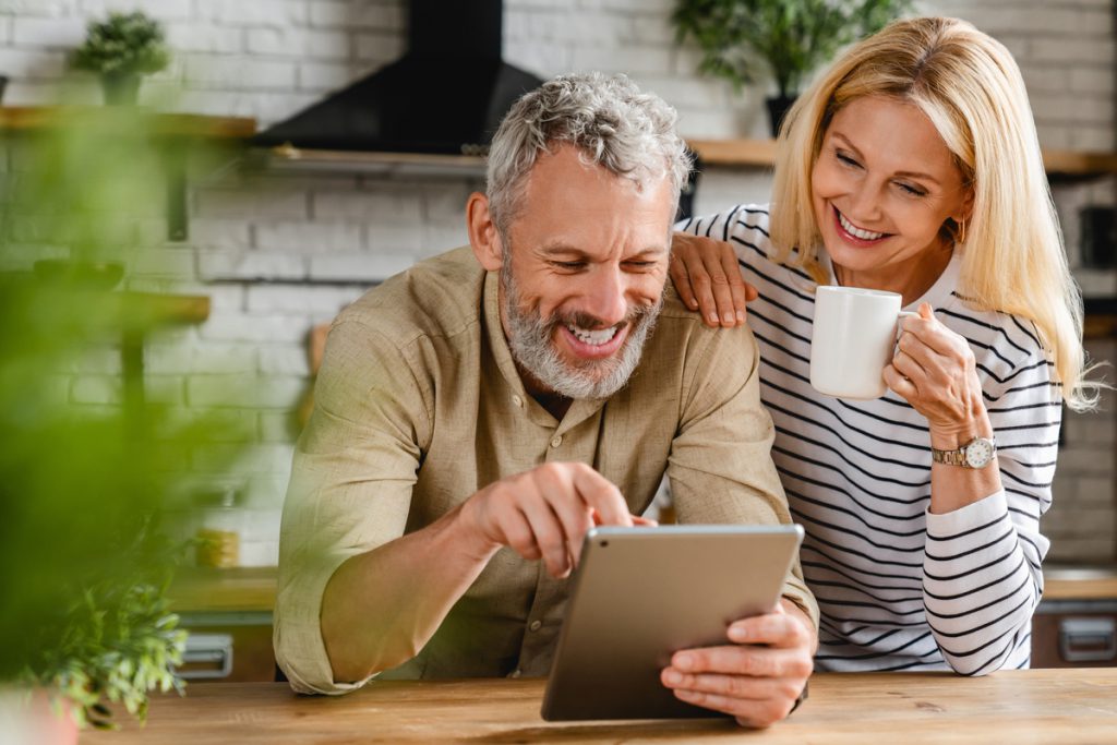 Happy senior couple using digital tablet in kitchen at home | Pension de reversion document Pôle emploi retraite