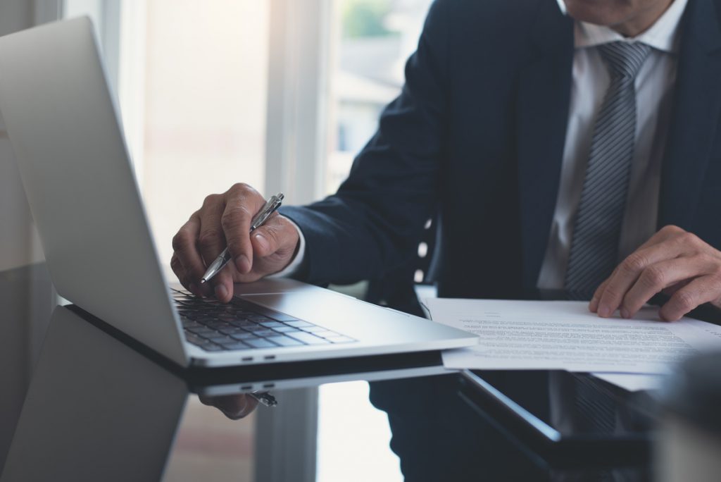 Businessman working on laptop computer with business contract on | Pension de reversion Retraite fonctionnaire