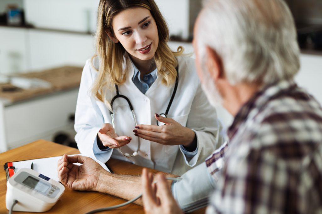 Happy female nurse measuring blood pressure of elderly man | Pension de reversion visiter EHPAD