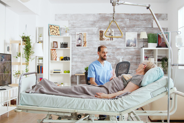 Male doctor having a conversation with ill old lady lying in hospital bed in a nursing home | Pension de reversion lit médicalisé gratuit