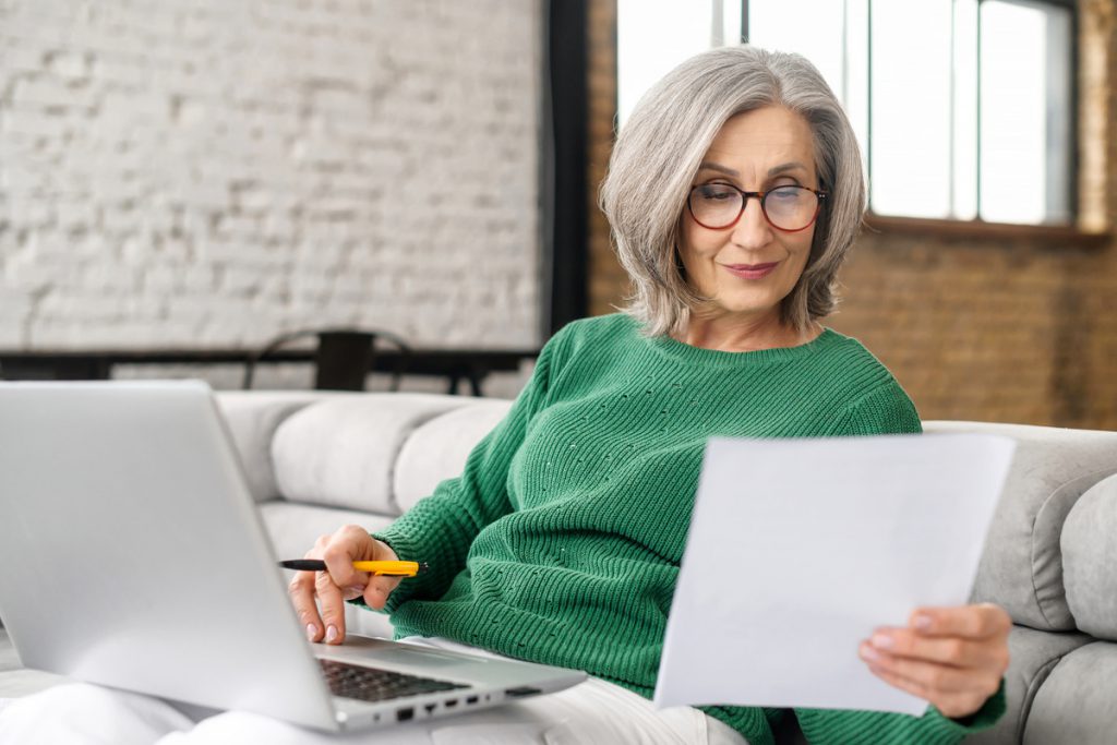 Mature senior woman using a laptop at home | Pension de reversion numéro de sécurité sociale