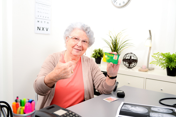 Senior woman in doctor's office showing her carte vitale medical french social security card | Pension de reversion pension de réversion et numéro de sécurité sociale