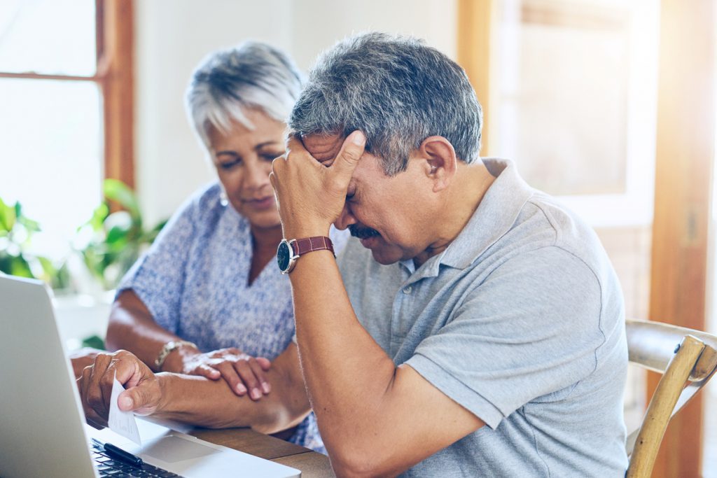 Debt, stress and senior couple with finance bills, paperwork and insurance documents on laptop. Retirement, anxiety and elderly man and woman worry for mortgage payment, investment and budget at home | Pension de reversion suspension de la retraite
