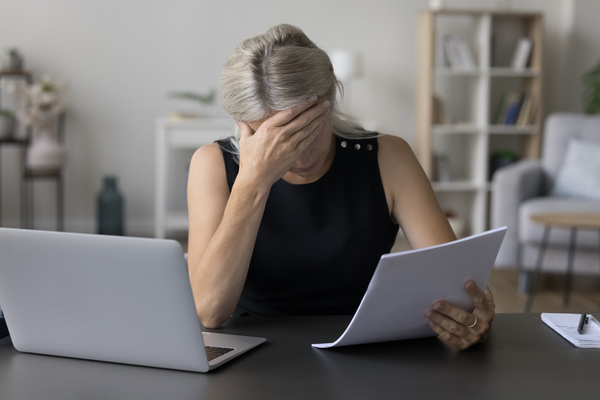 Depressed sad mature entrepreneur, business woman reading paper document | Pension de reversion retraite suspendue