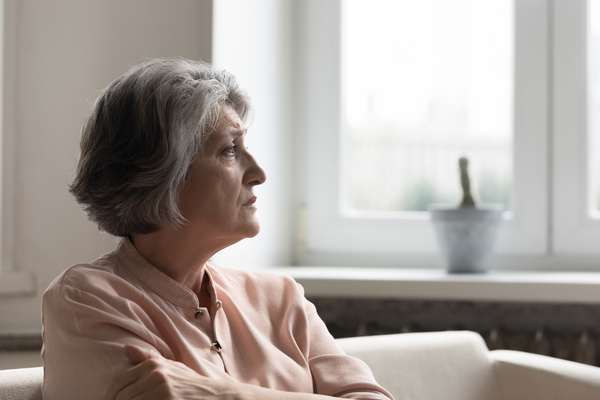 Concerned anxious senior 60s woman looking away, sitting on couch | Pension de reversion paiement anticipé de la pension de réversion