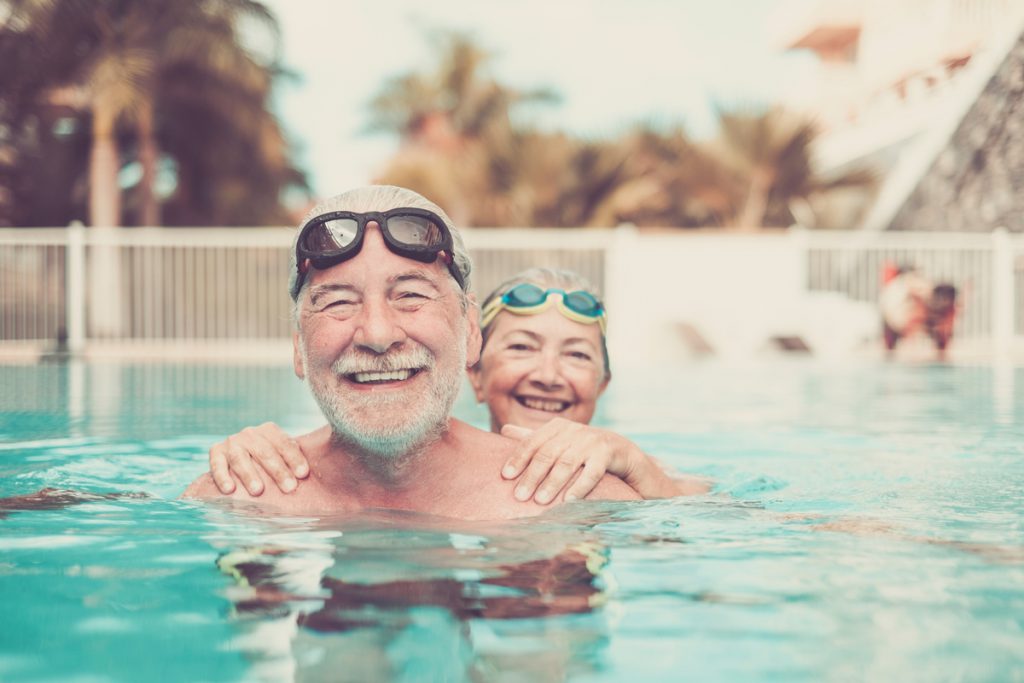 two seniors at the pool hugged together and playing - happy matu | Pension de reversion aide vacances seniors