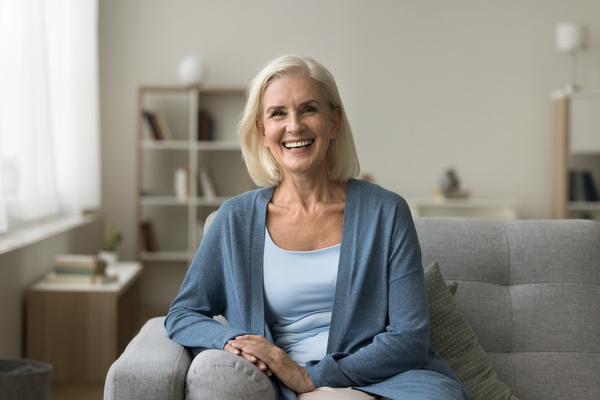 Happy pretty senior woman sitting on couch at cozy home | Pension de reversion aspa en septembre