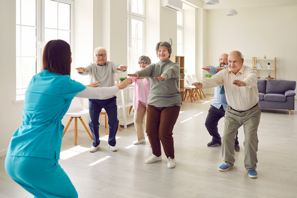 Senior group doing squat exercise with physiotherapist in gym | Pension de reversion activités en résidence autonomie