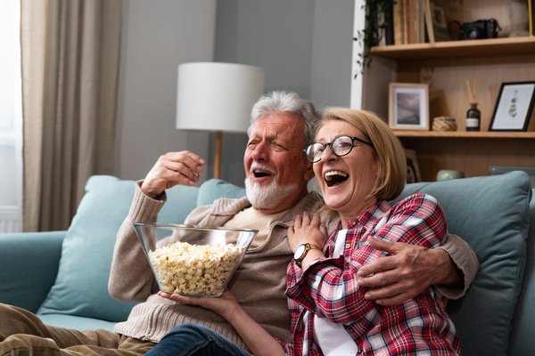 Old retired age couple watching TV at home, old mature couple cheering sport games competition together with laugh smile victory on sofa couch at living room home. Senior man and woman movie night. | Pension de reversion revenus complémentaire à la retraite