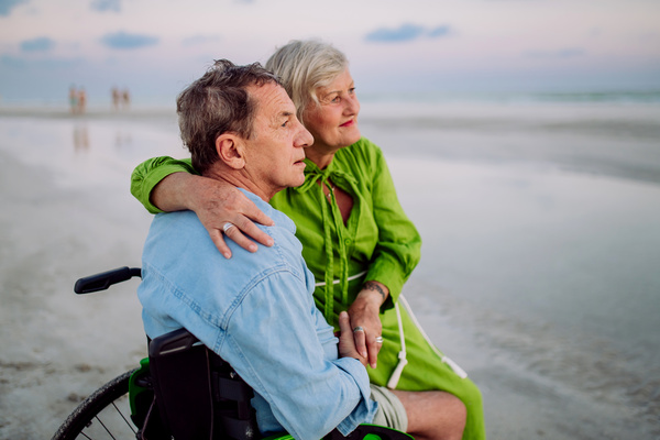 Senior man on wheelchair enjoying together time with his wife at sea. | Pension de reversion retraite expatriés