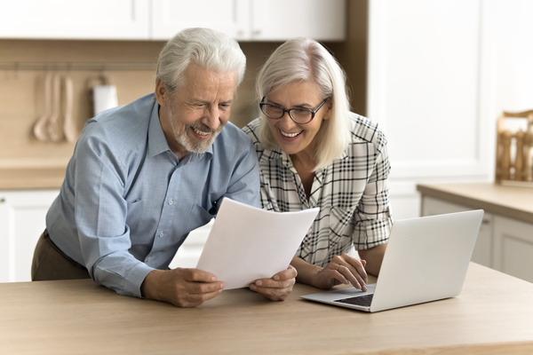 Happy satisfied senior retired couple reading legal document | Pension de reversion minoration de solidarité