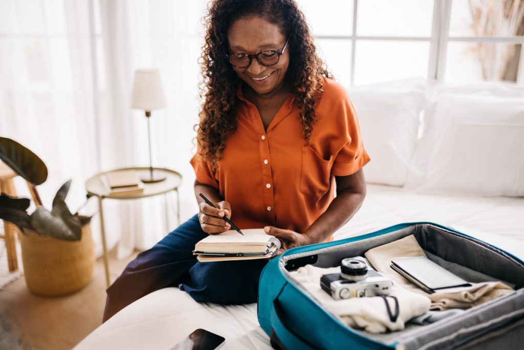 Senior woman getting ready for a vacation with a packing list | Pension de reversion chèques vacances