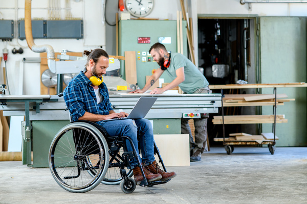 worker in wheelchair in a carpenter's workshop with his colleagu | Pension de reversion justificatifs demande de retraite anticipée