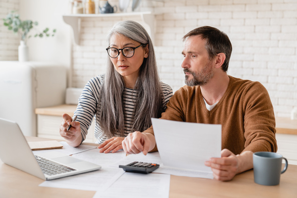 Mature middle-aged couple family wife and husband counting funds, savings declarations, investments,paperwork, financial documents, bankruptcy, court case, bills, pension with laptop. | Pension de reversion revalorisation des petites retraites