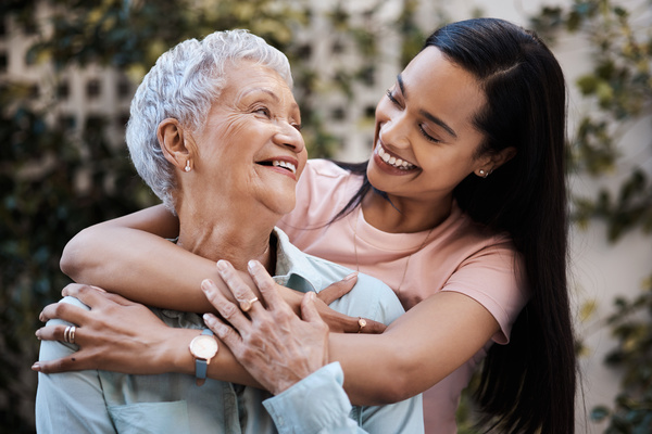 Happy, hug and loving of a mother and woman in a garden on mothers day with care and gratitude together. Smile, family and an adult daughter hugging a senior mom in a backyard or park for happiness | Pension de reversion conserver sa majoration Agirc Arrco