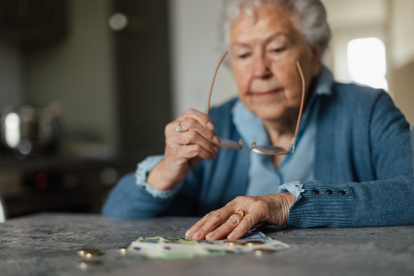 Senior woman counting her money at home. | Pension de reversion montant maximum retraite