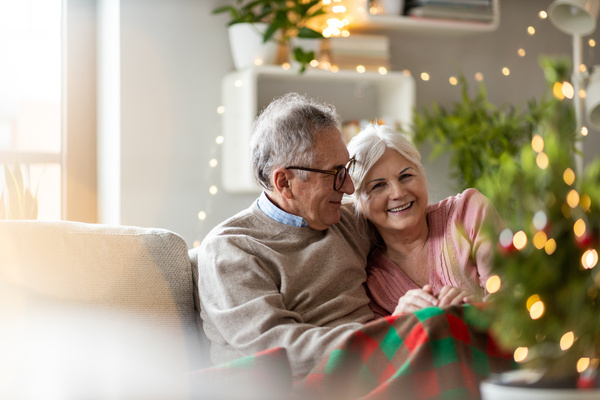 Senior couple sitting in the living room together during Christmas | Pension de reversion retraités à Noël