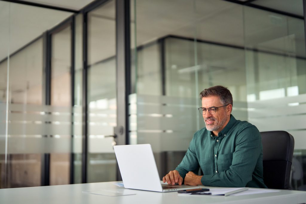 Smiling busy older professional business man working on laptop sitting at desk. | Pension de reversion estimer retraite