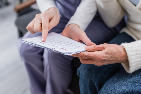 partial view of social worker pointing at calendar near aged wom | Pension de reversion paiement de la retraite décalé