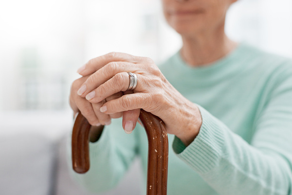 Hands, walking stick and elderly woman with walking stick on a sofa for balance, support and mobility. Walk, aid and old female at senior care facility with disability, dementia or chronic arthritis | Pension de reversion perte d'autonomie mandat de protection future