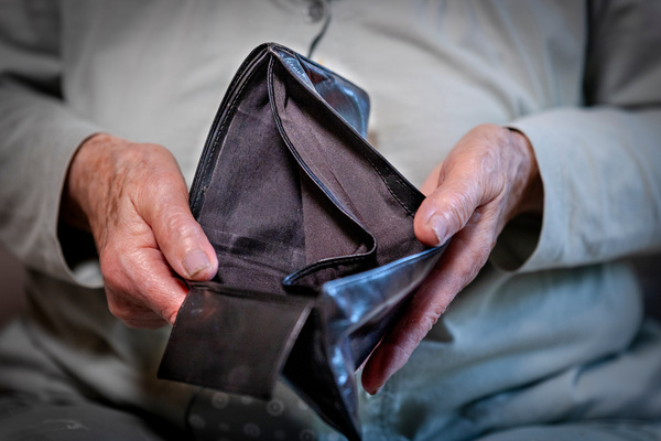 Rentnerin hält leeres Portemonnaie in der Hand | Pension de reversion ASS supprimée