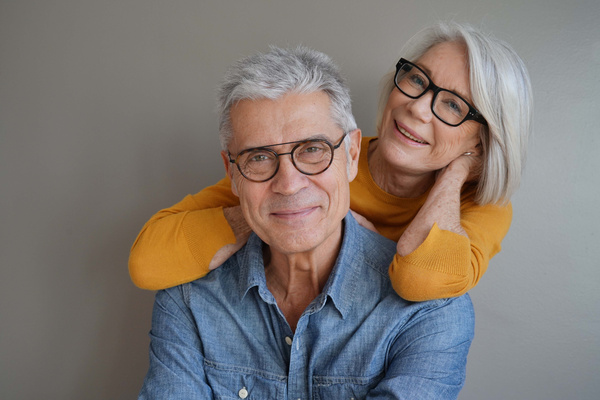 Portrait of relaxed fun senior couple wearing glasses on backgr | Pension de reversion 13ème mois retraite Suisse