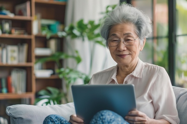 Smiling Chinese grandmother using a tablet at home highlighting modern senior lifestyle | Pension de reversion pays montant pension de retraite