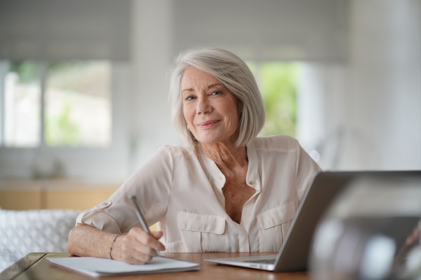Elderly woman working on computer at home | Pension de reversion retraite